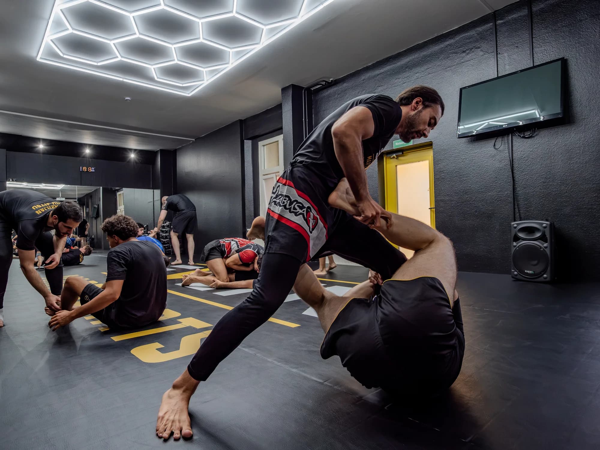 Zwei Sportler beim NoGi-Training unter den Hexagon-Leuchten im EVLTN Gym